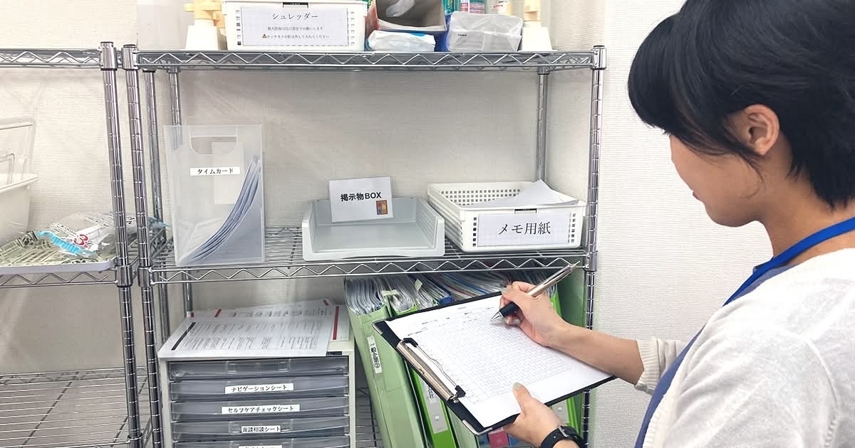 書類棚の前でクリップボードに記入するスタッフ
