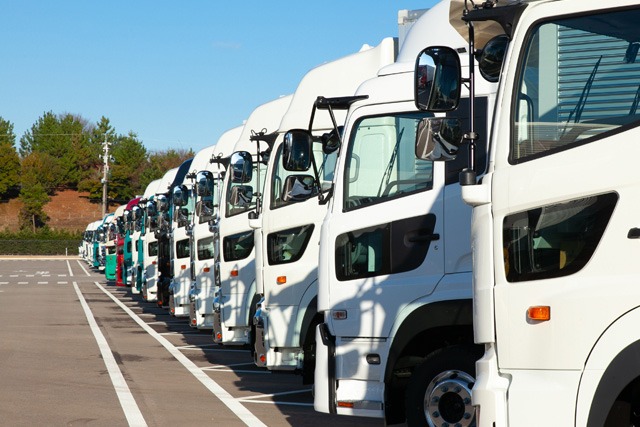 白いトラックが駐車場に一列に並んでいる様子。