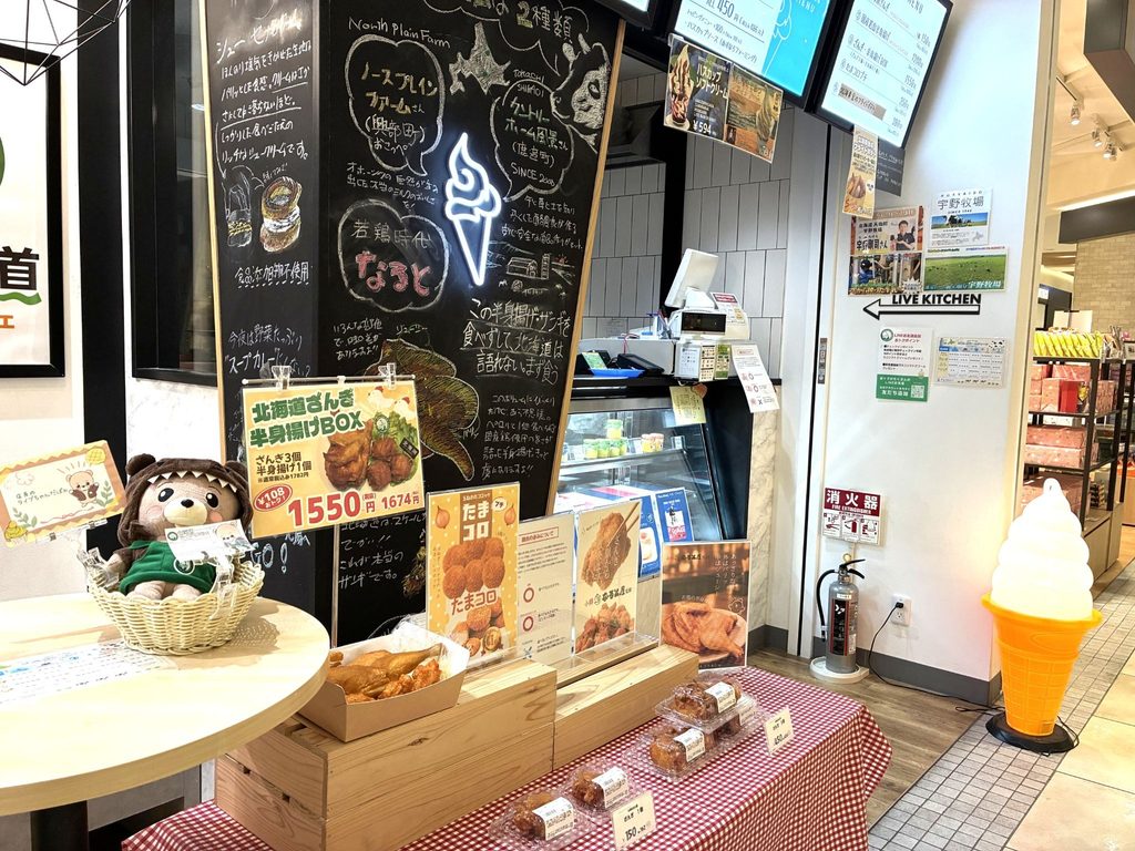 黒板メニューの前に、北海道ざんぎの半身揚げBOXやたまコロ、パック詰めの揚げ物が並ぶ売り場
