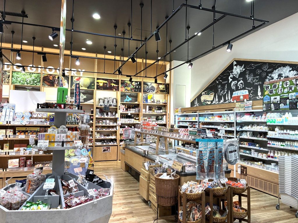 木目調の棚に商品が並ぶ店内。右手の黒板風の壁には魚や肉、フルーツのイラストが描かれている